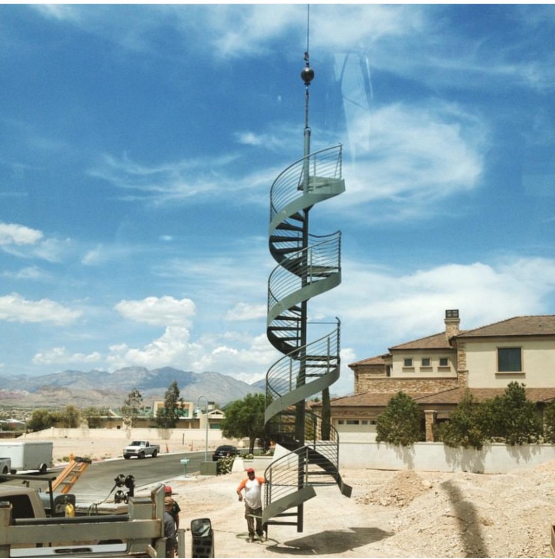A crane truck from Langford Crane Service, Inc. lifts a palm tree near a pedestrian sign, set against a clear blue sky and palm trees, demonstrating 50-ton crane rental in Las Vegas for landscaping work in progress.