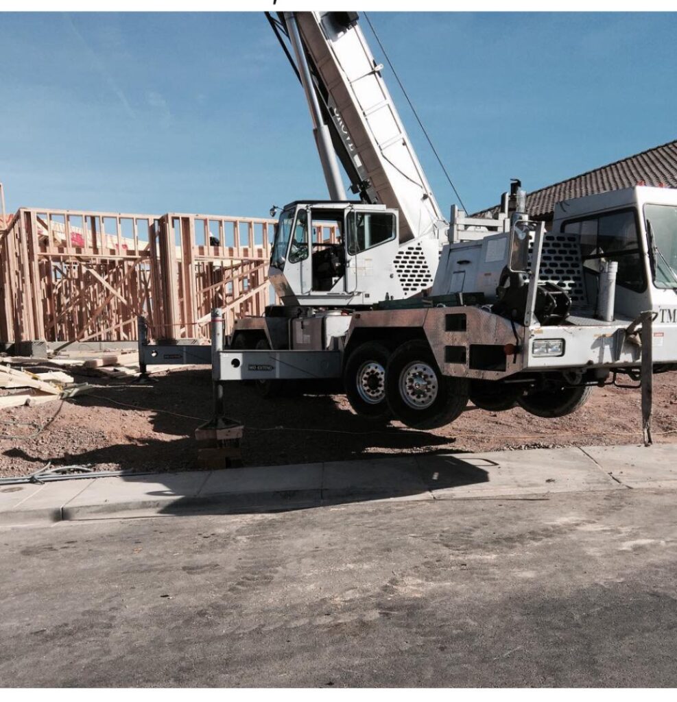 A crane positioned on a construction site next to a partially framed building, indicating active construction work in progress.